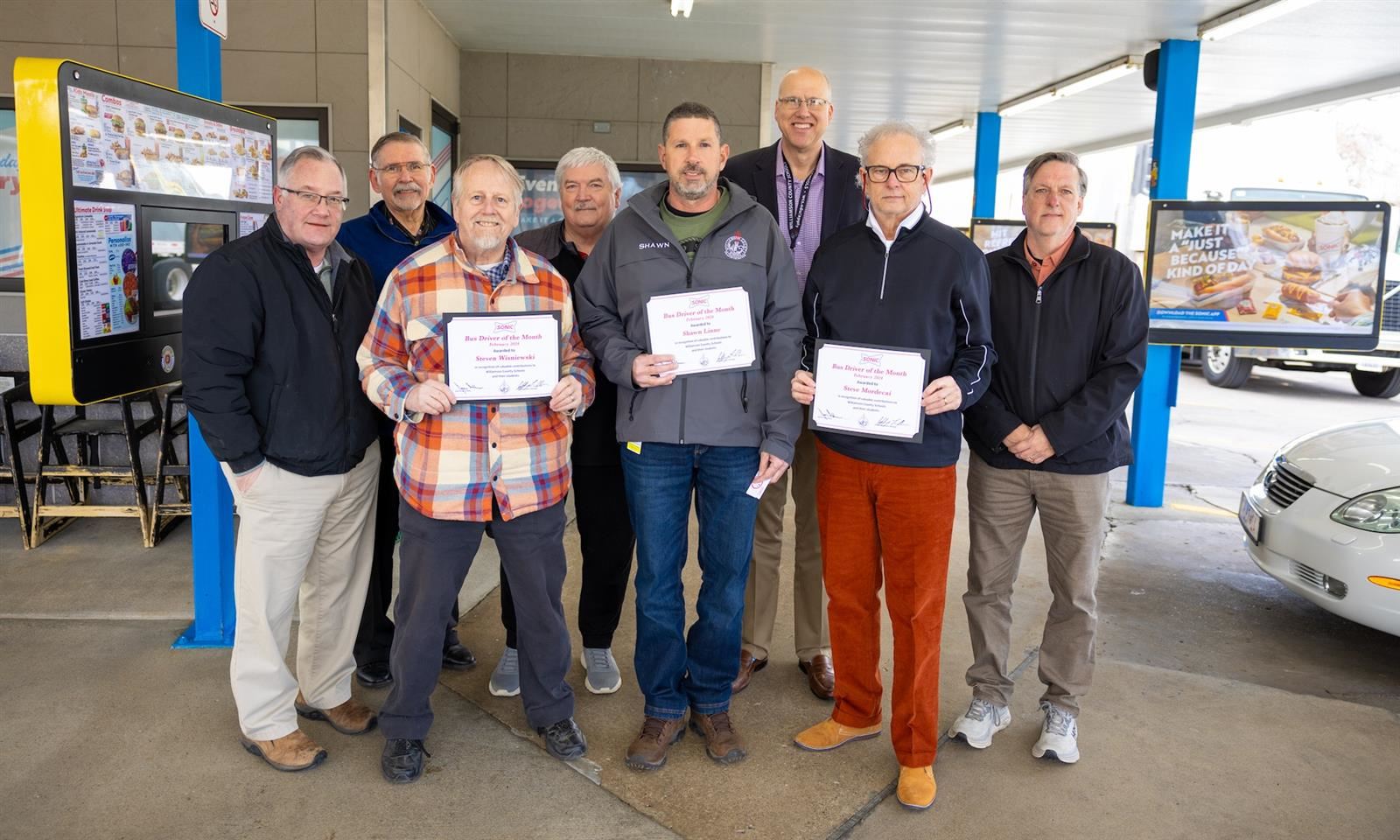Bus drivers smile and hold certificates
